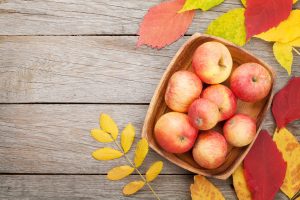 42663849 - apples in bowl and colorful autumn leaves on woden background with copy space
