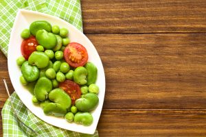 55971846 - broad bean, green pea and cherry tomato salad, photographed overhead on dark wood with natural light