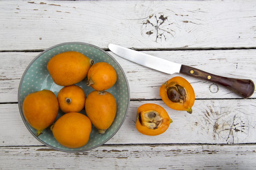 39780233 - medlar fruits in bowl on white wood