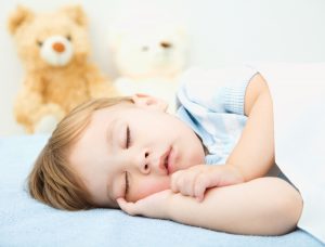 Cute little boy is sleeping in front of his teddy bears