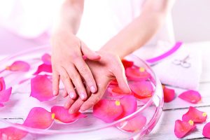 41293081 - smooth leather palm beauty treatment clinic.treatment hand and nail care women hold hands vial of rose oil over the bowl with rose petals