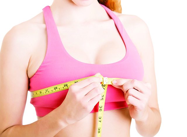 50143308 – sporty woman measuring up her chest, isolated in white