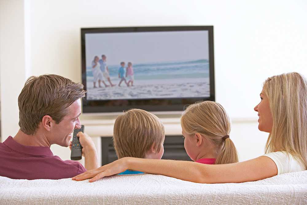 Family Watching Widescreen TV At Home