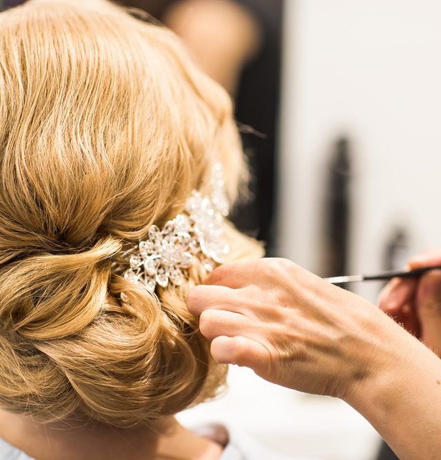 Hair stylist makes the bride before a wedding