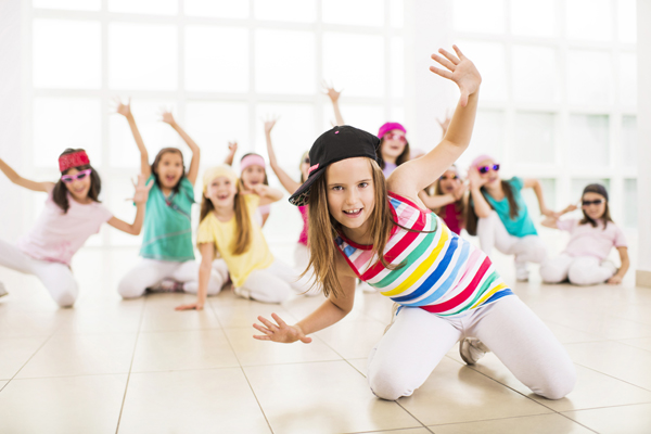 Group of little girls dancing. Focus is on foreground, on a little girl in a dance move looking at the camera.