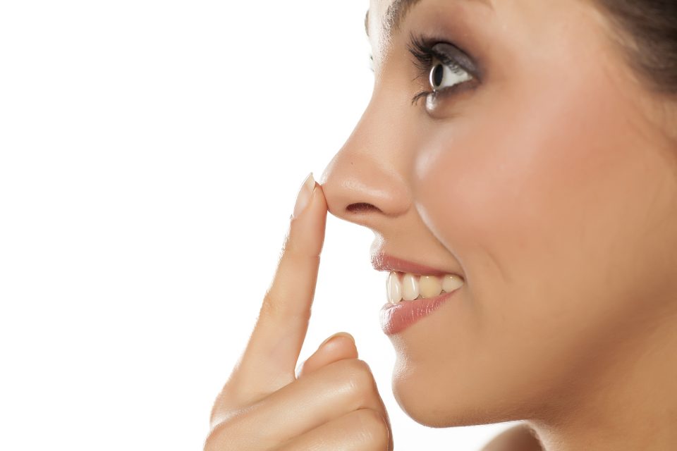 Profile of young smiling woman touching her nose